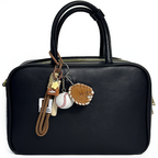 A black leather handbag with a baseball-themed keychain attached to its handle, featuring a brown carabiner clip, a yellow star charm, a brown coffee cup charm, a brown leather baseball glove, and a white baseball with red stitching.