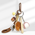 A baseball-themed keychain with a brown carabiner clip, featuring a yellow star charm, a brown lidded coffee cup charm with "cafe" text, a brown leather baseball glove, a wooden baseball bat, and a white baseball with red stitching, attached to a braided rope strap.