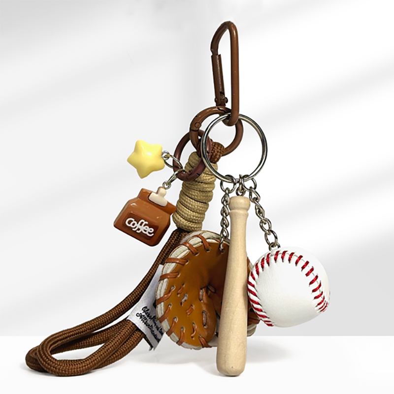 A baseball-themed keychain with a brown carabiner clip, featuring a yellow star charm, a square brown coffee cup charm with "coffee" text, a brown leather baseball glove, a wooden baseball bat, and a white baseball with red stitching, attached to a braided rope strap.