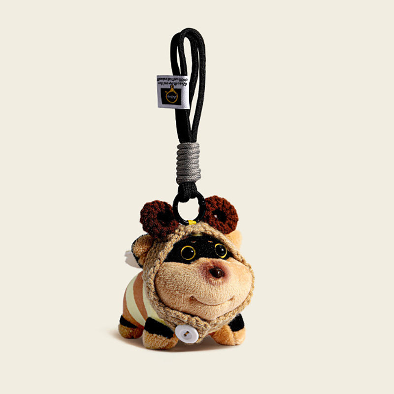 A plush bee-dog bag charm in a striped yellow and black bee costume with brown crocheted antennae, attached to a black carabiner clip with a white tag. The charm features a smiling face and a white button on its chest, designed as a cute and trendy accessory for bags or keychains.