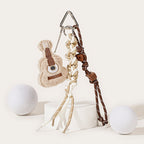 A beige plush guitar keychain with brown string embroidery, attached to a silver carabiner with a mixed brown and white braided rope strap and brown star-shaped beads.