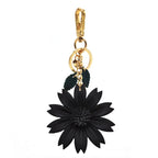 A sleek black leather flower keychain displayed against a plain white backdrop. It hangs from a shiny gold-tone clip and ring assembly, with matching dark green leaf details adding contrast.