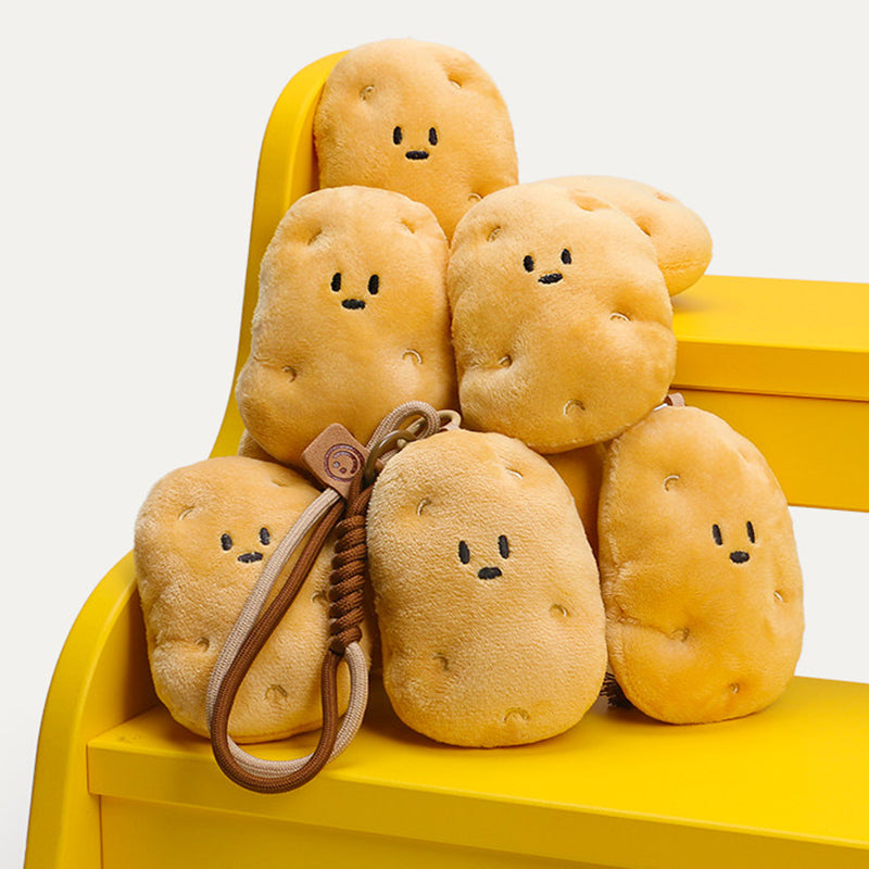 A group of cute plush potato keychains with simple smiling faces, arranged on a yellow chair. One keychain in the foreground features a brown leather strap with a woven detail and a small leather tag with a smiley face logo, showcasing the design of these trendy and adorable accessories.