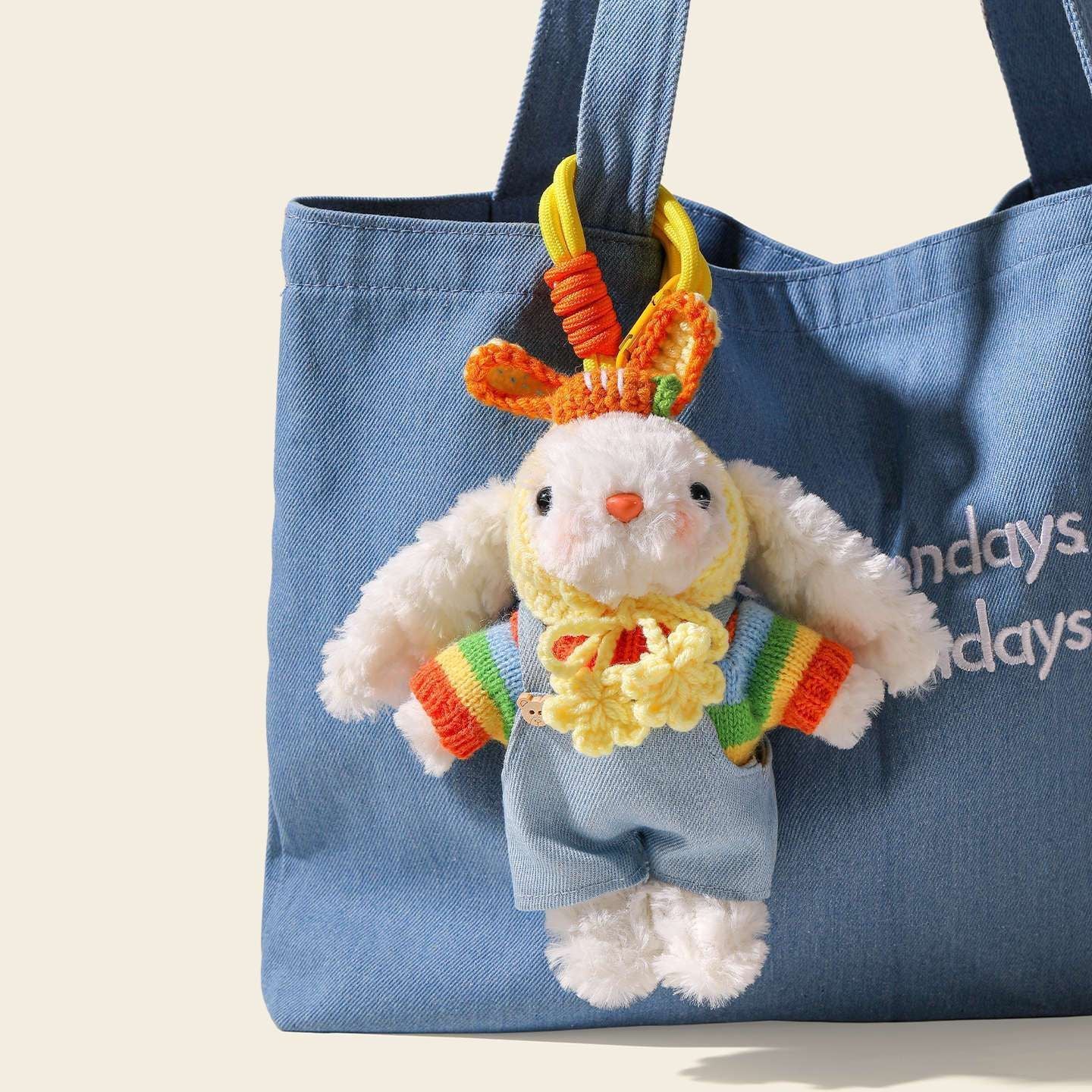 A white plush rabbit bag charm with long floppy ears, wearing a colorful striped sweater and blue overalls, topped with a crocheted orange hat, hanging from a blue canvas bag as a cute and trendy bag charm.
多巴胺垂