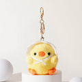 A yellow plush chick keychain emerging from a white eggshell, with black embroidered eyes, an orange beak, and orange feet, adorned with a white ribbon bow, attached to a gold-tone metal carabiner and keyring.
