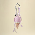 A lavender leather ice cream cone bag charm with a white scalloped edge and perforated details, attached to a silver carabiner clip. It features lavender and white ribbons, a pearl chain, and a small silver heart charm, designed as a cute and trendy accessory for bags or keychains.