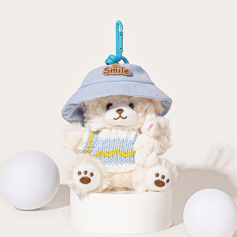 A white teddy bear plush keychain wearing a light blue bucket hat with a "Smile" patch and a light blue and white knit sweater with a yellow stripe, holding a small white rabbit plush, attached to a light blue carabiner clip.