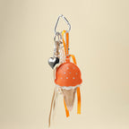An orange leather ice cream cone bag charm with a white scalloped edge and perforated details, attached to a silver carabiner clip. It features orange and white ribbons, a pearl chain, and a small silver heart charm, designed as a cute and trendy accessory for bags or keychains.
