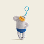 A plush duck-billed platypus bag charm in white fabric with blue pants, a yellow beak, and black dots on its body. It is attached to a blue carabiner clip, featuring a playful and unique design for bags or keychains.