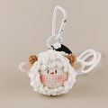A close-up of a white crocheted sheep plush keychain with brown ears and a smiling face, attached to a white carabiner clip.