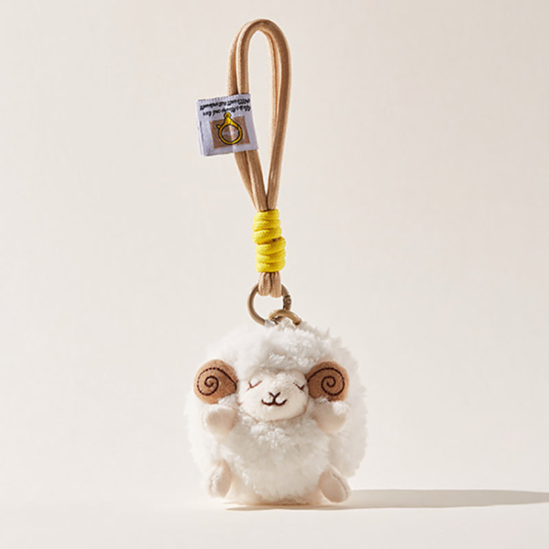 A front-facing view of a white fluffy sheep plush keychain with brown spiral horns and a smiling face, attached to a beige cord with a yellow wrap and a small branded tag.